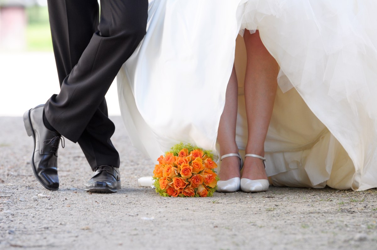 Ein Hochzeitsfoto von einer Braut und einem Bräutigam, aber nur die Beine sind fotografiert.