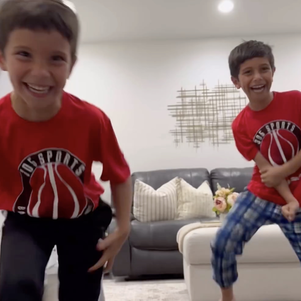 Zwei Jungen hüpfen lachend durch ein Wohnzimmer.