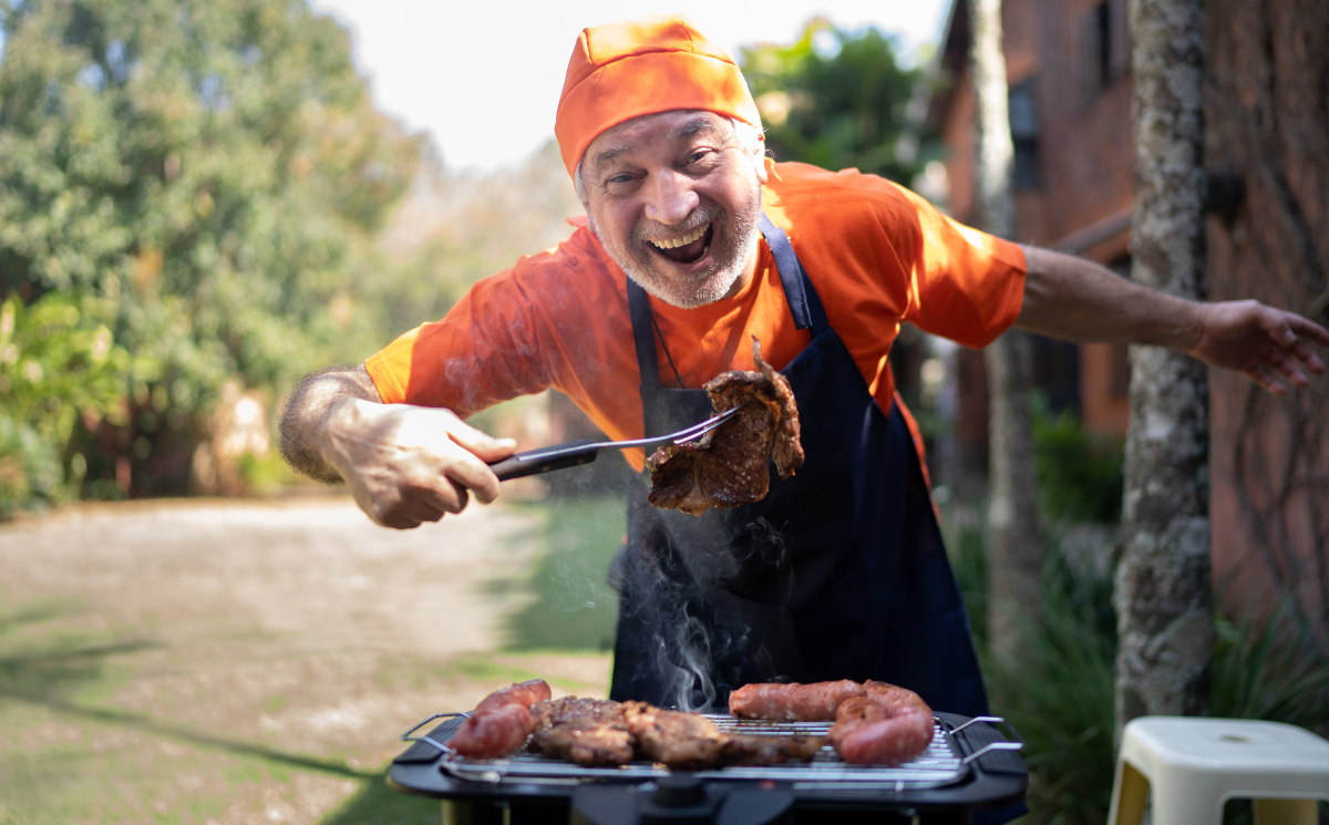Ein Bild von einem glücklichen Rentner, der Fleisch auf einem Grill zubereitet.
