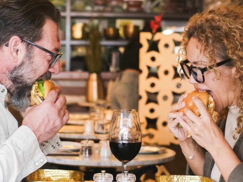Ein glückliches Paar ist Hamburger in einem Restaurant.