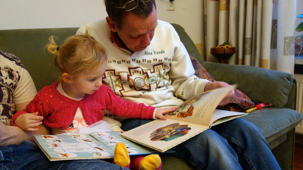 Ein Mann schaut sich mit einem kleinen Mädchen ein Bilderbuch an.