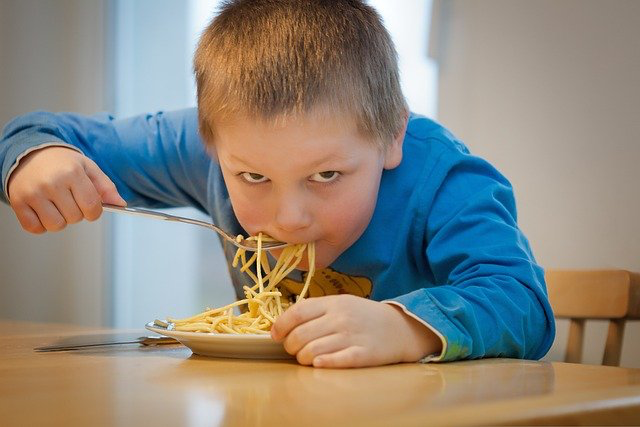 Ein blonder Junger isst Spaghetti