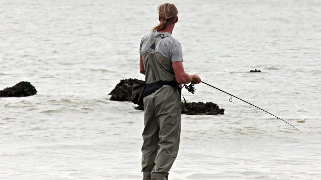 Ein Angler steht im Wasser und fischt.