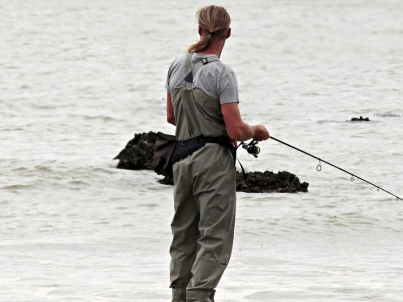 Ein Angler steht im Wasser und fischt.