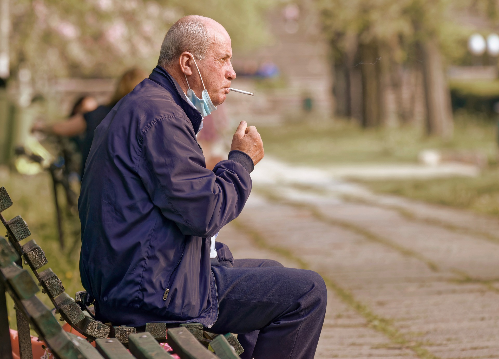 Ein alter Mann, der auf einer Parkbank raucht.