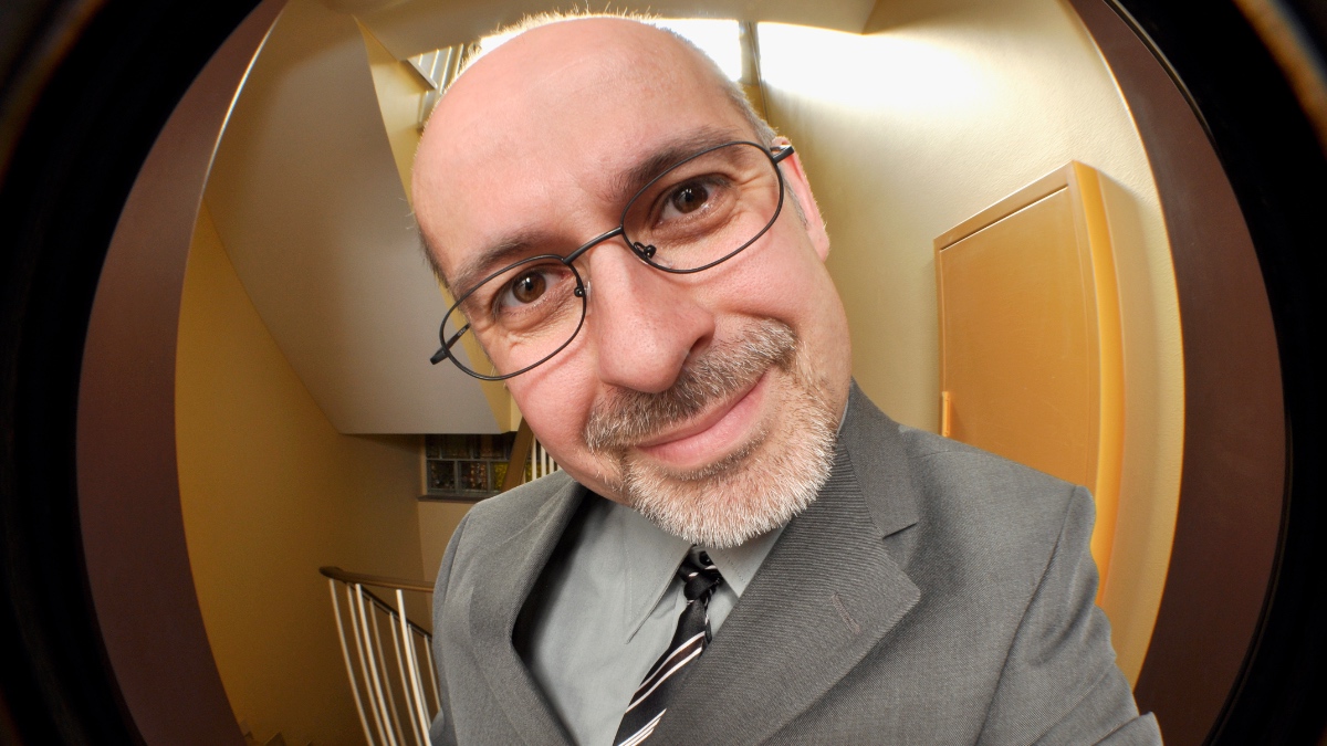 Ein Foto von einem Vertreter in grauem Anzug und Brille durch einen Türspion fotografiert.