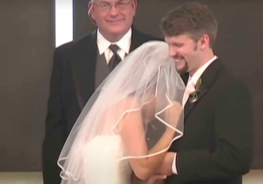 Eine lachende Braut umarmt den Bräutigam vor dem Altar.