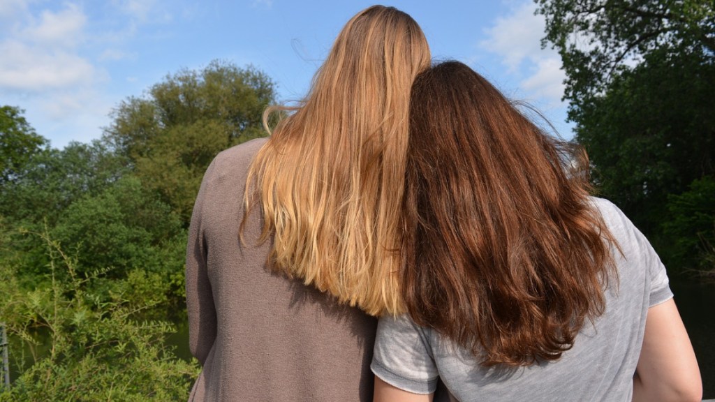Eine Frau lehnt den Kopf an die Schulter ihrer Freundin.