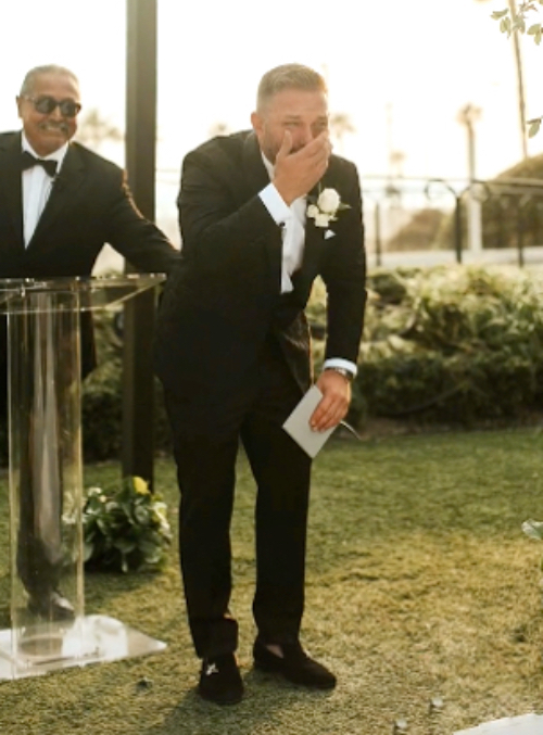 Ein Bräutigam in Anzug hält sich überrascht die Hand vor den Mund.