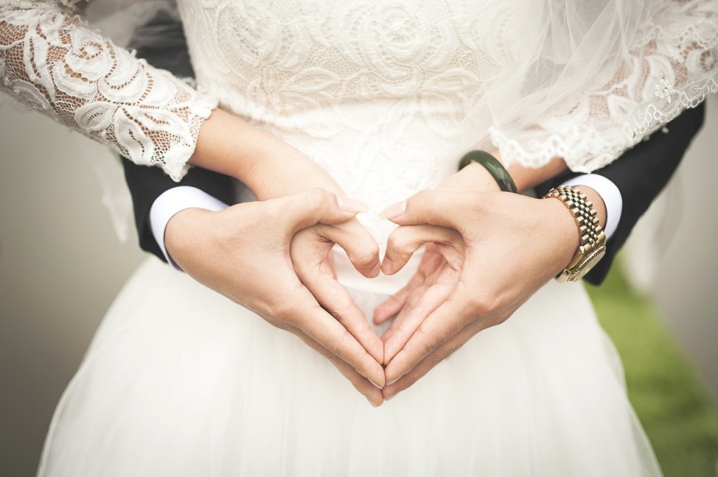 Ein Hochzeitspaar formt mit den Händen ein Herz