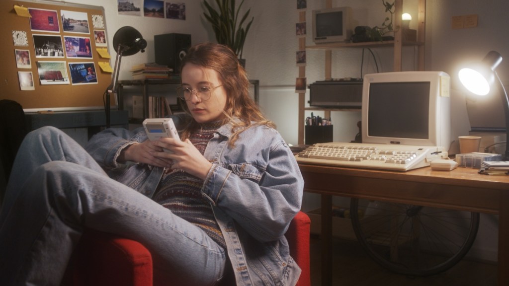 Ein Mädchen in den 90er-Jahren spielt in ihrem Zimmer mit einem Gameboy.