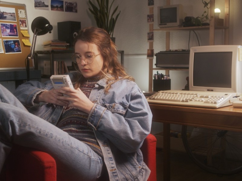 Ein Mädchen in den 90er-Jahren spielt in ihrem Zimmer mit einem Gameboy.