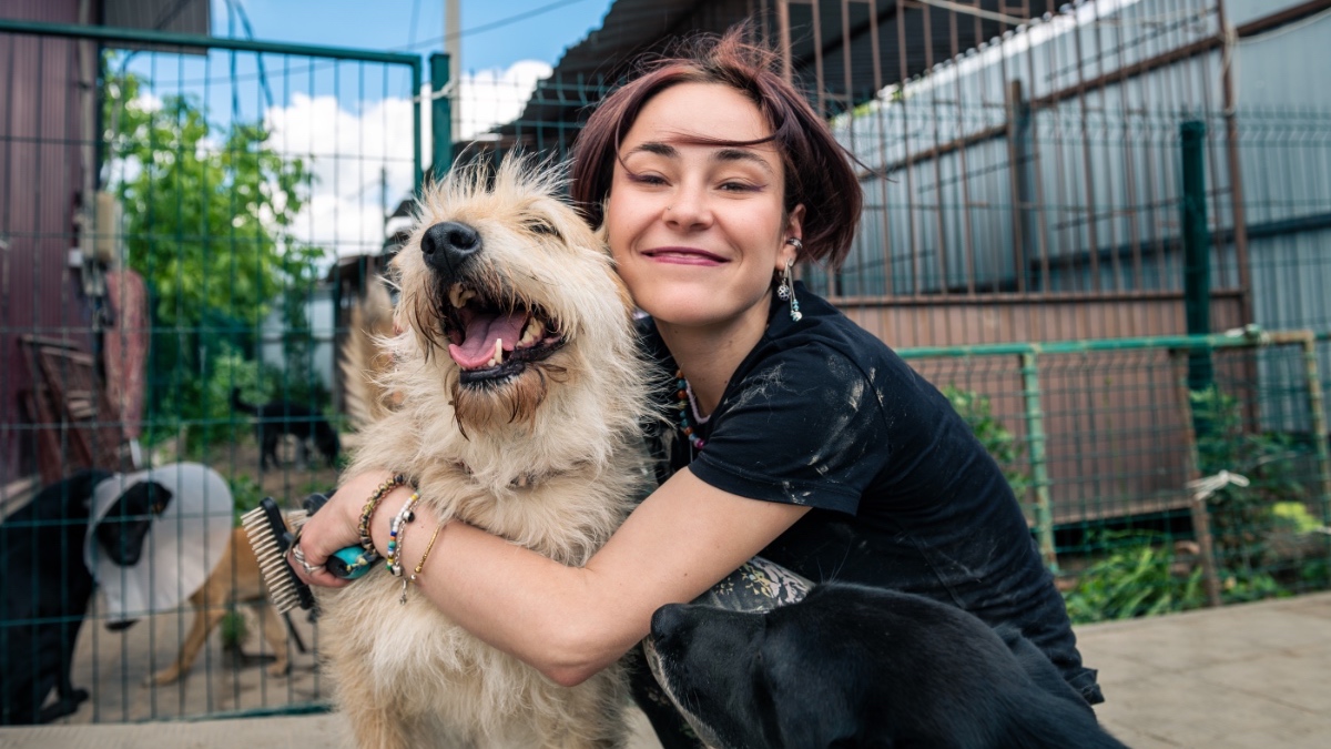 Ein Hund wird in einem Tierheim von einer Frau umarmt.