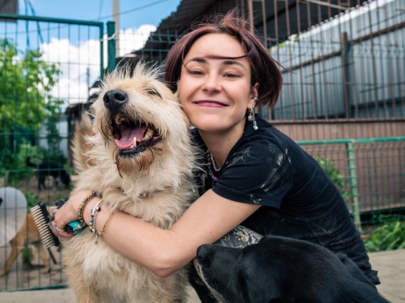 Ein Hund wird in einem Tierheim von einer Frau umarmt.