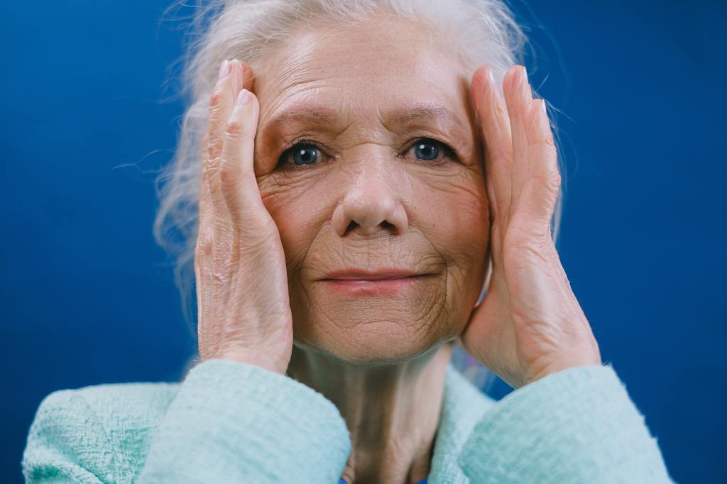 Eine ältere Frau fasst sich an den Kopf.