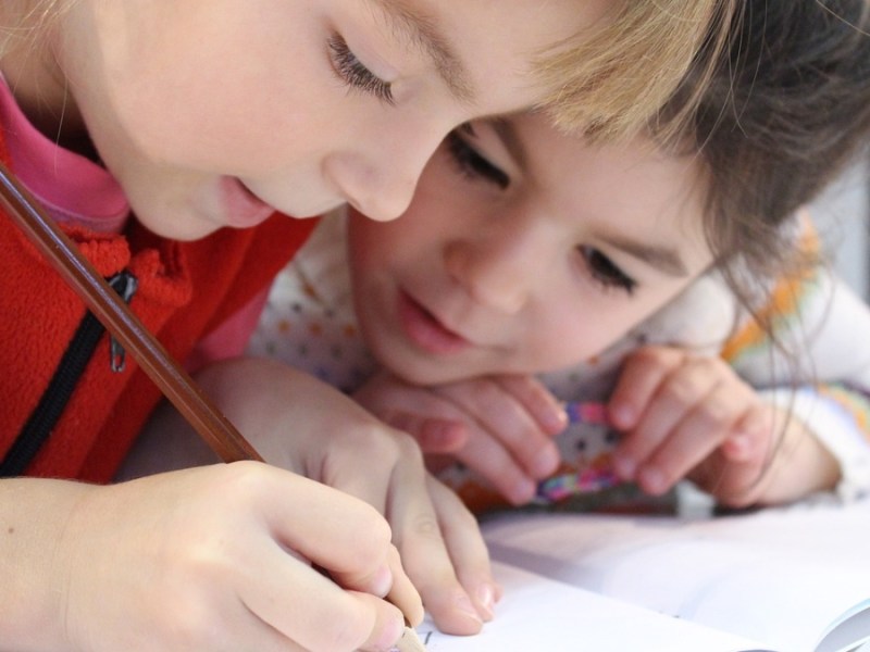 Zwei kleine Mädchen schreiben in ihrem Schulfheft.