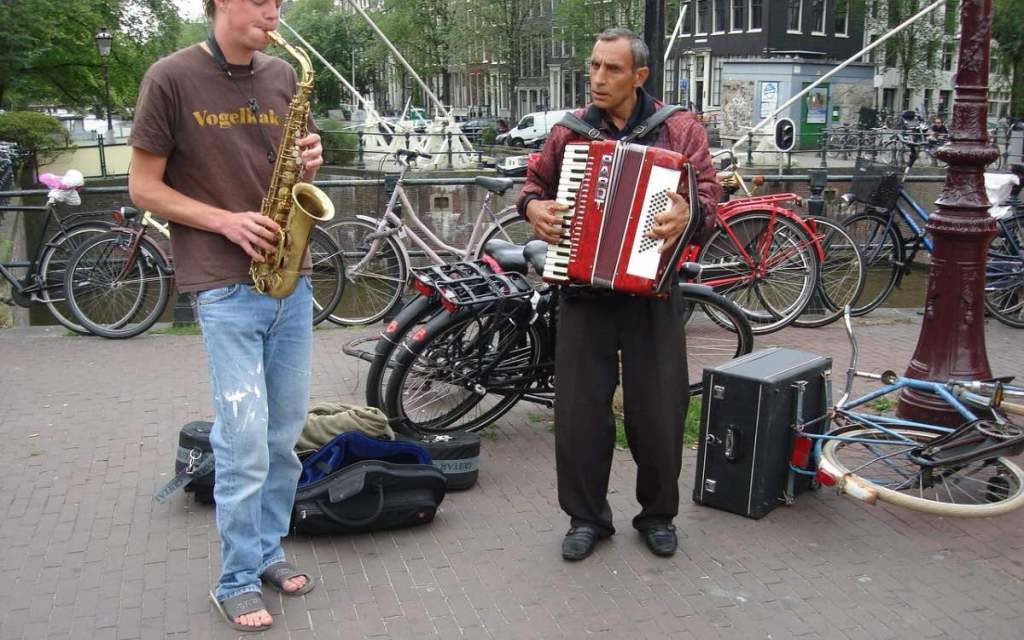 Zwei Straßenmusiker machen Musik in einer Fußgängerzone.