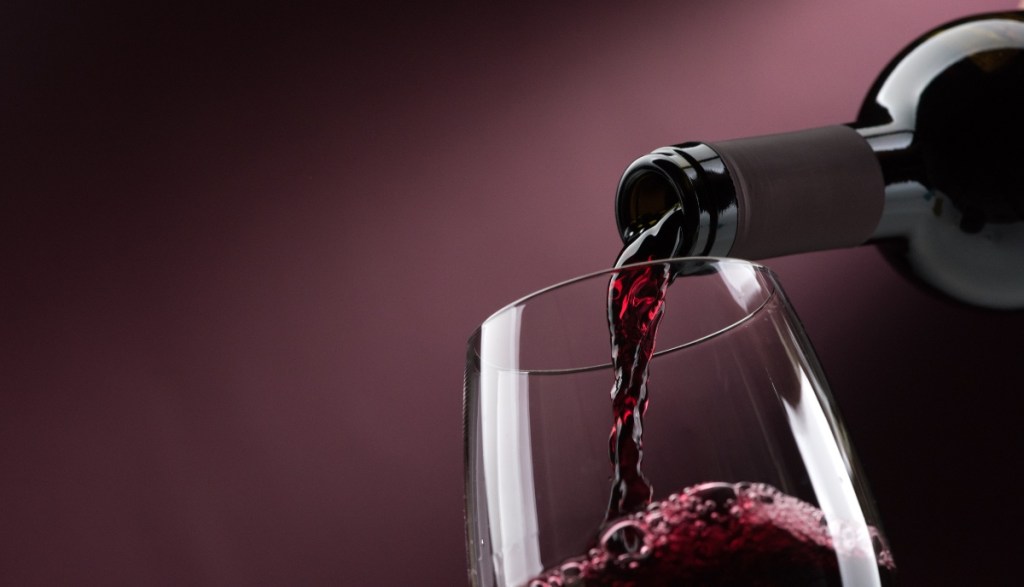 Rotwein wird in ein Glas eingeschenkt.