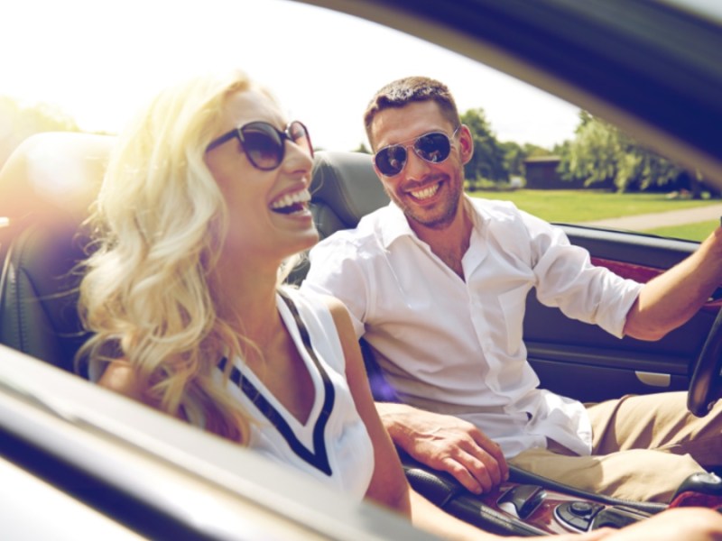 Glücklicher Mann und glückliche Frau fahren in einem Cabrio Auto.