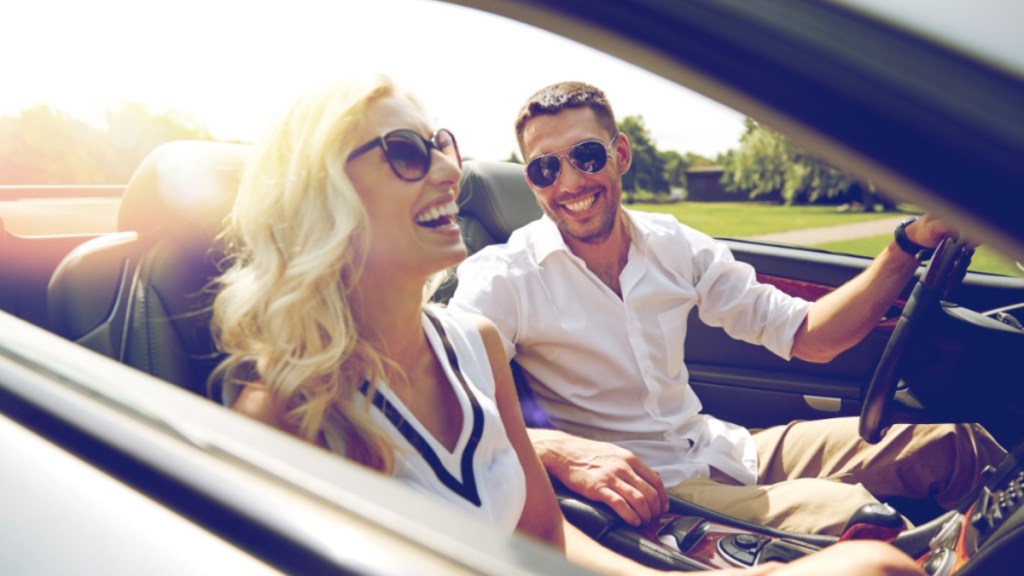 Glücklicher Mann und glückliche Frau fahren in einem Cabrio Auto.