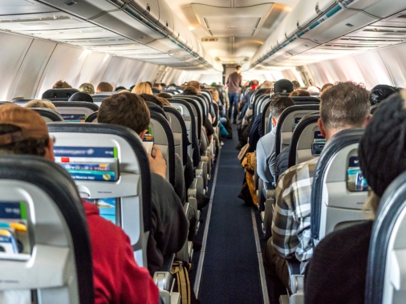 Passagiere in einem kommerziellen Passagierflugzeug sitzend.