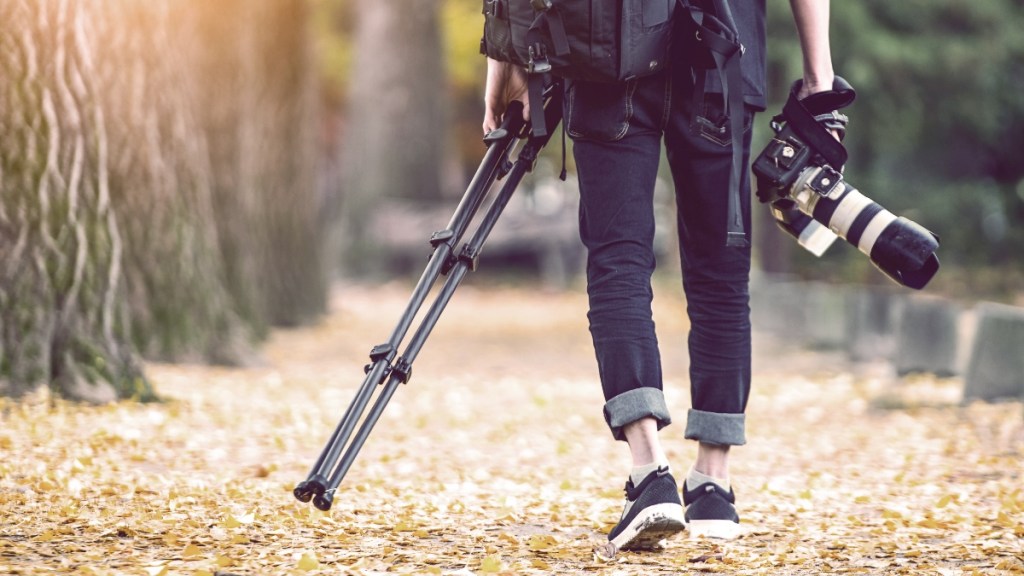 Professioneller Fotograf mit Kamera und Stativ im Herbst.