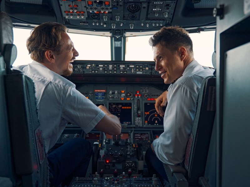 Zwei Piloten im Cockpit, die lachen.