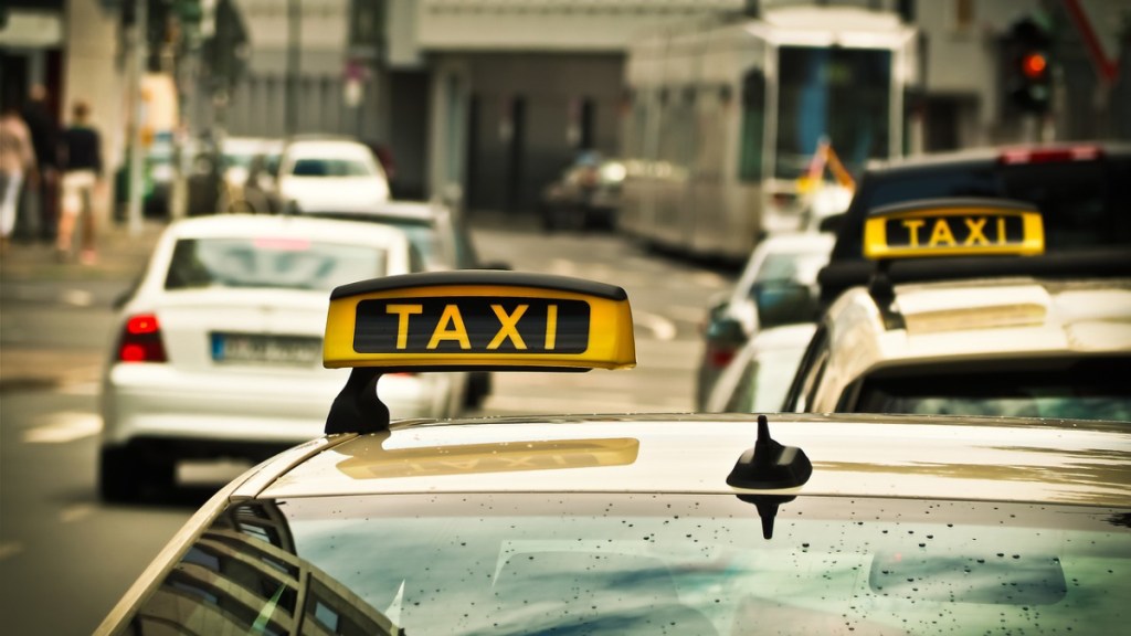 Das Schild eines Taxis, das am Straßenrand steht.