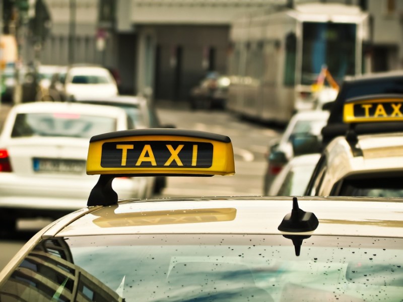 Das Schild eines Taxis, das am Straßenrand steht.