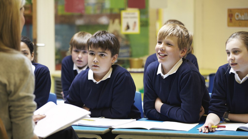 Kinder mit Schuluniform hören im Unterricht ihrer Lehrerin zu.