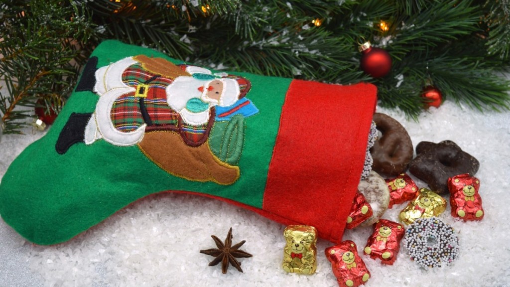 Ein mit Süßigkeiten gefüllter Strumpf liegt vor einem Weihnachtsbaum.
