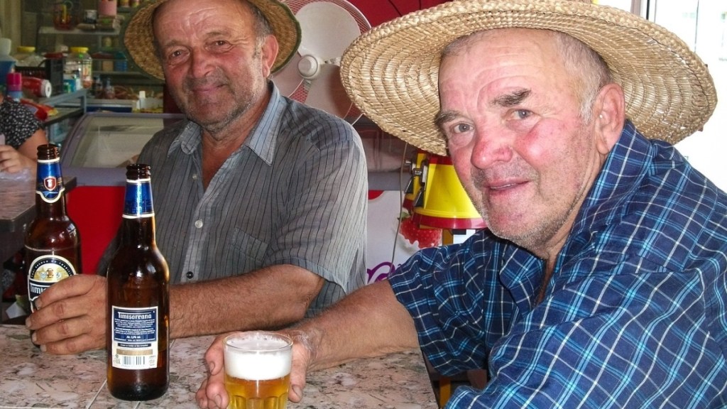 Zwei Männer mit Strohhut trinken Bier in einer Kneipe.