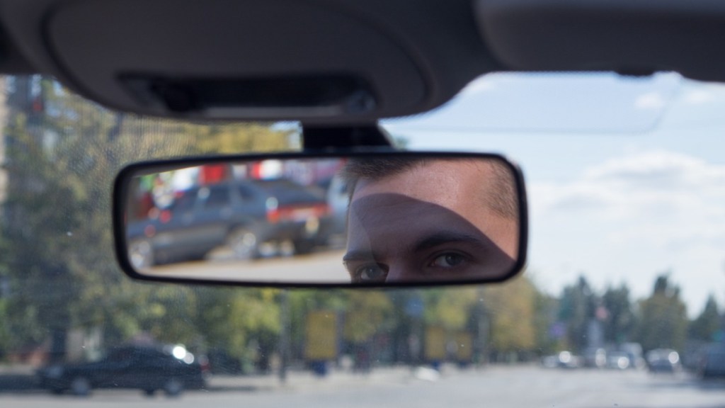 Ein Taxifahrer schaut in seinen Rückspiegel.