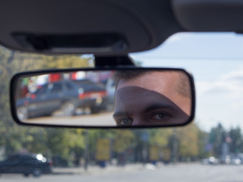 Ein Taxifahrer schaut in seinen Rückspiegel.