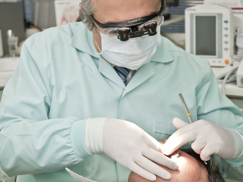 Ein Zahnarzt mit Mundschutz behandelt einen Patienten.