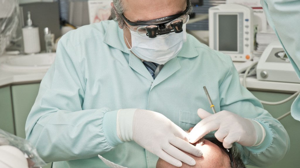 Ein Zahnarzt mit Mundschutz behandelt einen Patienten.