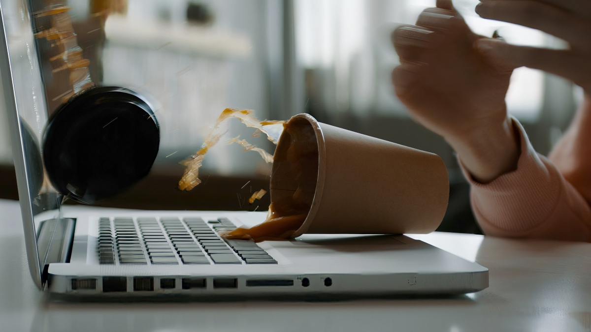 Eine Tasse Kaffee fällt auf einen Laptop.