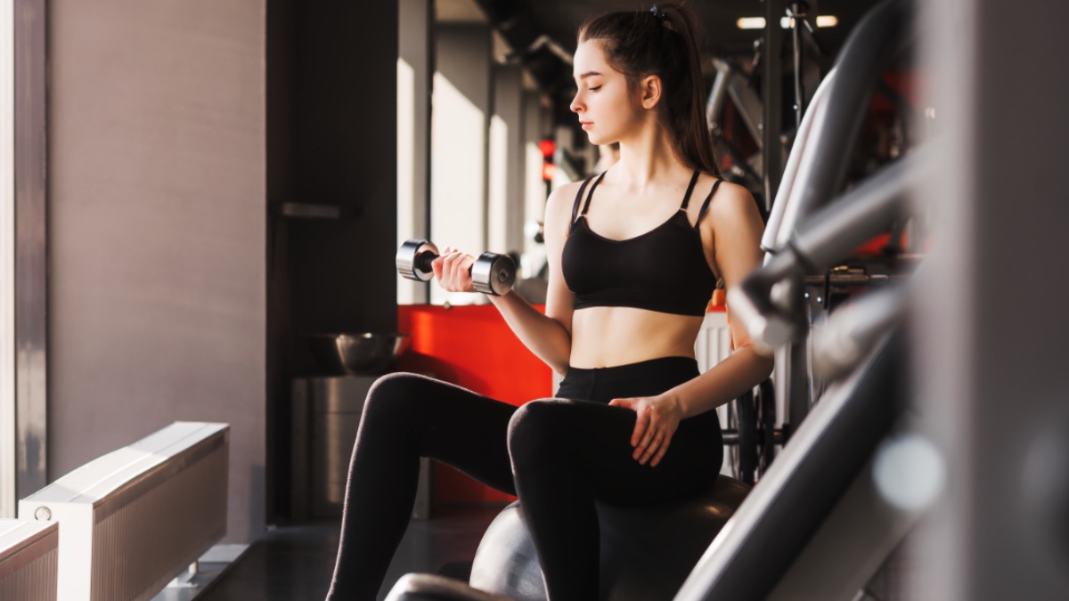 Junge Frau trainiert mit einer Hantel im Fitnessstudio.