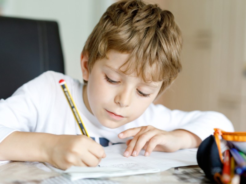 Ein blonder Junge macht seine Hausaufgaben.