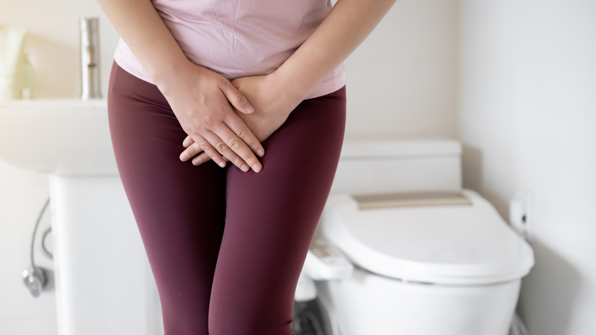 Eine Frau halt sich auf einer Toilette die Hand vor den Bauch.