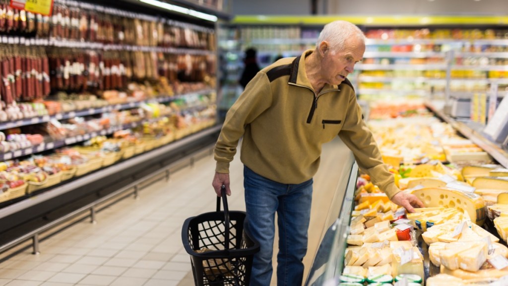 Ein alter Mann kauft Käse in einem Supermarkt ein.