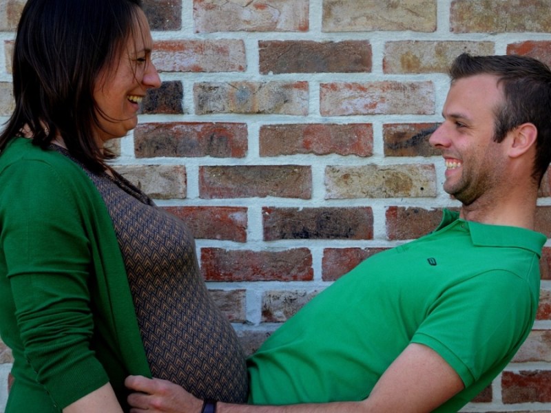 Eine schwangere Frau posiert mit ihrem Partner in einem lustigen Foto.