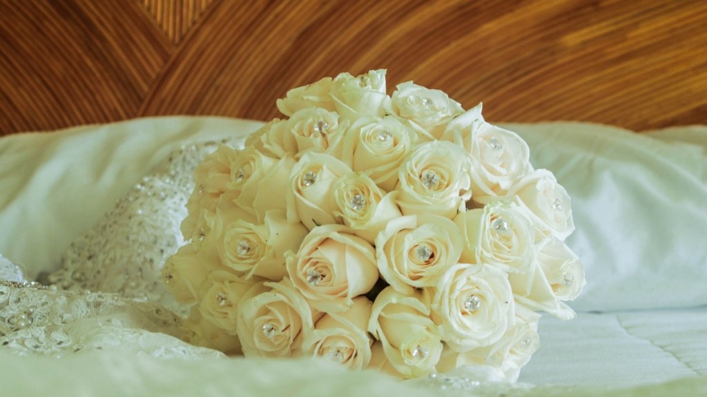 Ein Foto von einem Blumenstrauß mit weißen Rosen, die auf einem Bett liegen.