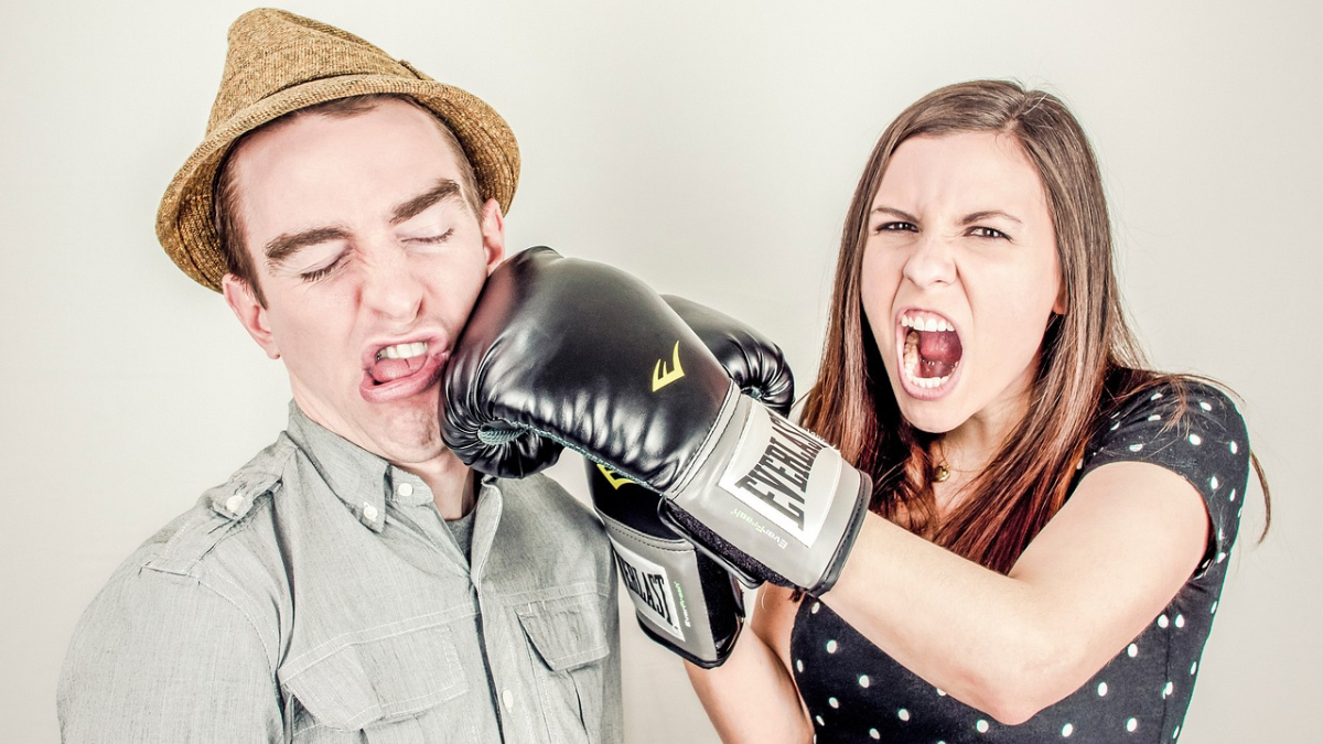 Eine junge Frau schlägt einem Mann mit einem Boxhandschuh ins Gesicht.
