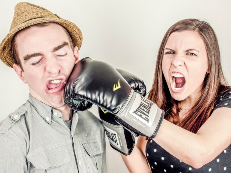 Eine junge Frau schlägt einem Mann mit einem Boxhandschuh ins Gesicht.