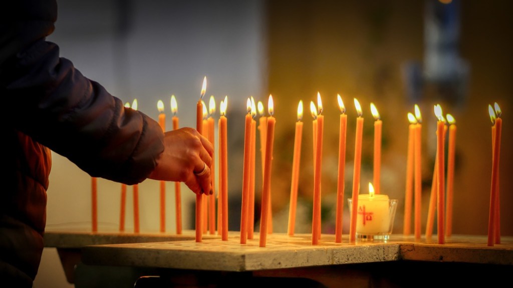 Ein Mann zündet eine Kerze in einer Kirche an.