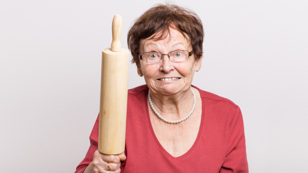 Ein Bild einer wütenden Rentnerin, die drohend ein Nudelholz in der Hand hält.