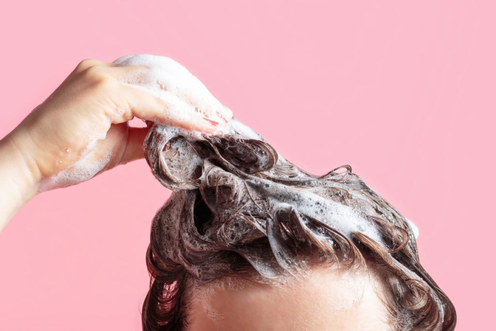 Ein Mädchen wäscht sich die Haare mit Shampoo.
