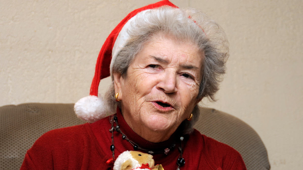 Eine alte Frau mit Weihnachtmütze auf einer Weihnachts-Party.