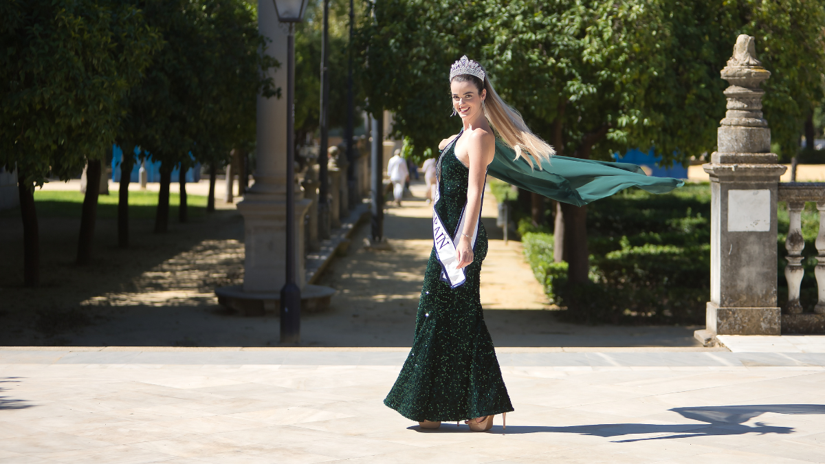 Eine Schönheitskönigin in einem grünen Kleid vor einer Allee fotografiert.